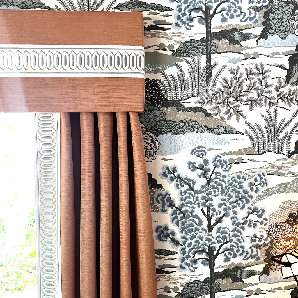 Brown curtain with white trim against a decorative wallpaper with tree patterns
