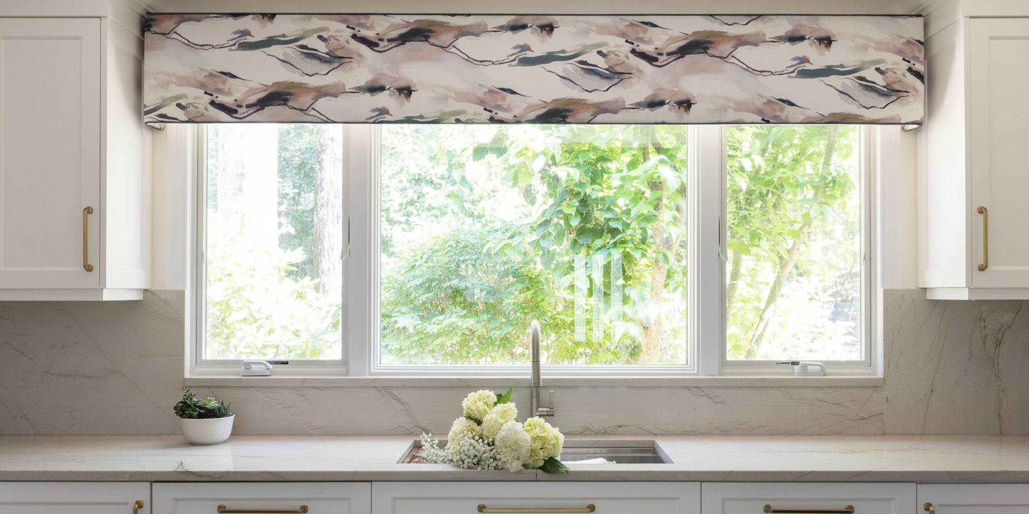 Kitchen with a window featuring a floral patterned valance, sink, and decorative elements.